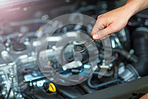 Mechanic working on car engine in auto repair shop