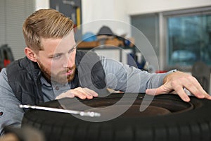 mechanic working on car wheel in workshop