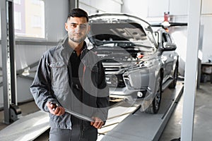 Mechanic working and holding wrench of service order for maintaining car at the repair shop