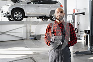 Mechanic working and holding wrench of service order for maintaining car at the repair shop