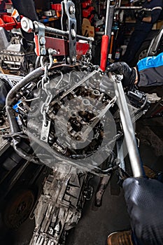 Mechanic Working on Suspended Car Engine with Manual Hoist