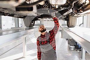 Mechanic working under car at the repair garage. Auto mechanic working in garage. Repair service