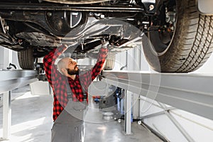 Mechanic working under car at the repair garage. Auto mechanic working in garage. Repair service