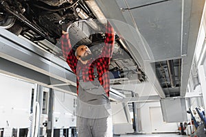 Mechanic working under car at the repair garage. Auto mechanic working in garage. Repair service