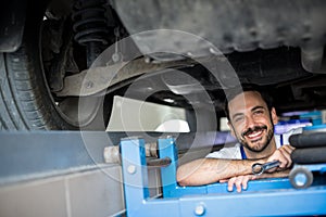 Mechanic working under car smiling