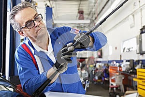 Mechanic working on windshield wipers of car