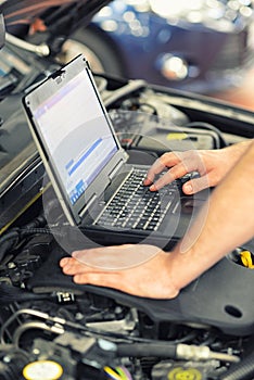 Mechanic in a workshop checks and checks the electronics of the car - software update with a modern computer
