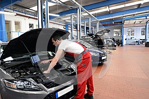 mechanic in a workshop checks and checks the electronics of the car - software update with a modern computer