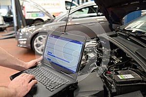mechanic in a workshop checks and checks the electronics of the car - software update with a modern computer