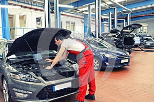 Mechanic in a workshop checks and checks the electronics of the car - software update with a modern computer