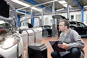 Mechanic in a workshop checks and inspects a vehicle for defects