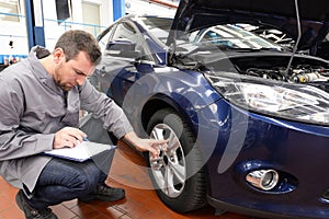 Mechanic in a workshop checks and inspects a vehicle for defects