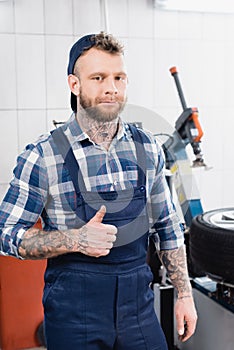 Mechanic in workwear showing thumb up