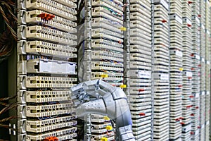 The mechanical arm of the robot is next to the switchboard of the ip telephony. The robot works in the server room of the data