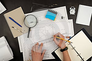 Mechanical drawing on sheets of paper. Hands on the table top view. Workflow of an architect, engineer. Write and draw