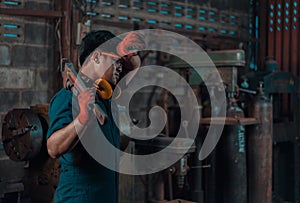 Mechanical engineer taking a break and wiping sweat off his forehead while resting a pipe wrench on his shoulder during