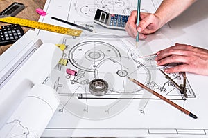 Mechanical engineer with work at technical drawings and work tools,