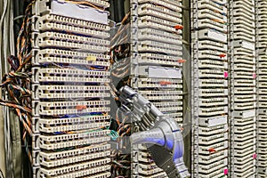 A mechanical hand is next to the ip telephony patch panel. The robot switches wires to switchboards