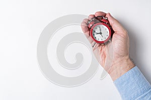 Mechanical red alarm clock in male hands on white background. Time management concept. Top view