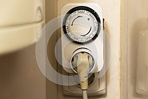 Mechanical socket timer with a circular dial, plugged into a wall outlet