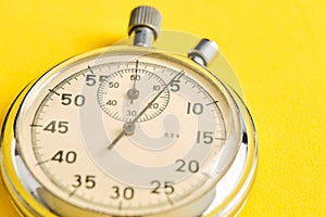 Mechanical stopwatch yellow background closeup.