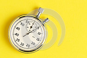 Mechanical stopwatch yellow background closeup.