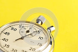 Mechanical stopwatch yellow background closeup.