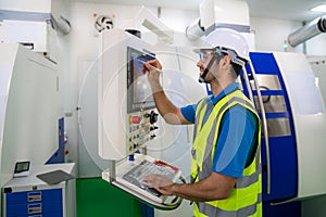 Mechanical technician operative entering data in cnc milling cutting machine at factory at tool workshop in metal machining photo