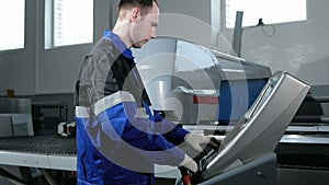 Mechanical technician programming punching the machine CNC. A man enters the data carefully to control panel. Metal is