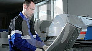 Mechanical technician programming punching the machine CNC. A man enters the data carefully to control panel. Metal is