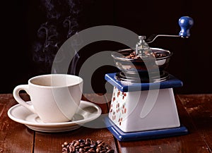 Mechanical vintage coffee grinder and coffee cup on the table