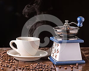 Mechanical vintage coffee grinder and coffee cup on the table