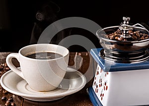 Mechanical vintage coffee grinder and coffee cup on the table