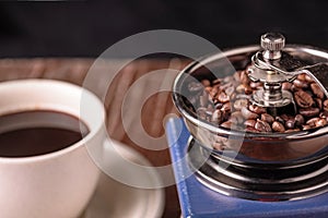 Mechanical vintage coffee grinder and coffee cup on the table