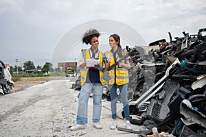 Mechanical woman owner small business inspecting standing in the car junkyard, Dirty male repairman choosing spare parts on car