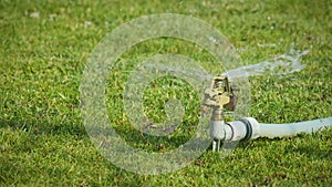 Mechanically garden water sprayer left on a dry summer day lawn