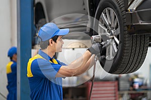 Mechanician changing car wheel in auto repair shop