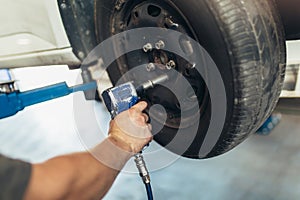 Mechanician changing car wheel in auto repair shop