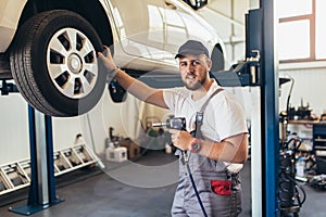 Mechanician changing car wheel in auto repair service photo