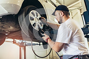 Mechanician changing car wheel in auto repair shop photo