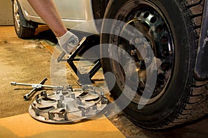 Mechanician changing car wheel in garage. Man exchanging tire. Tire service.