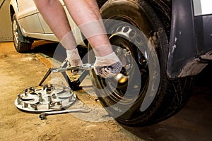 Mechanician changing car wheel in garage. Man exchanging tire. Tire service. photo