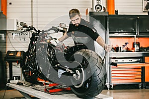 Mechanician changing motorcycle wheel in bike repair shop.