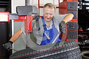 Mechanician removing tire from wheel disc photo