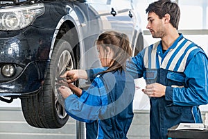 Mechanics Changing Tire From Suspended Car At Garage