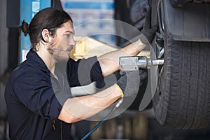 Mechanics Fixing Car Tires At Garage