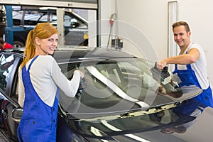 Mechanics or glaziers install windshield or windscreen on car