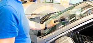 Mechanics man changing the broken windshield and automobile windshield or windscreen replacement of white car in Auto