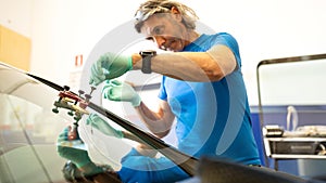 Mechanics man changing the broken windshield and automobile windshield or windscreen replacement of white car in Auto