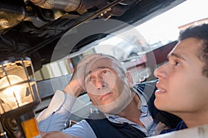 Mechanics in pit looking at undercarriage vehicle